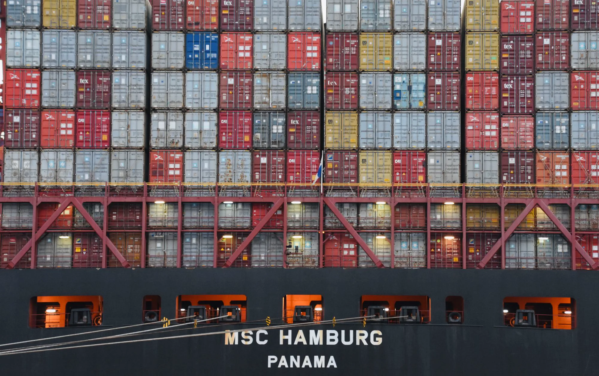 Rows of stacked steel shipping containers in a port yard.